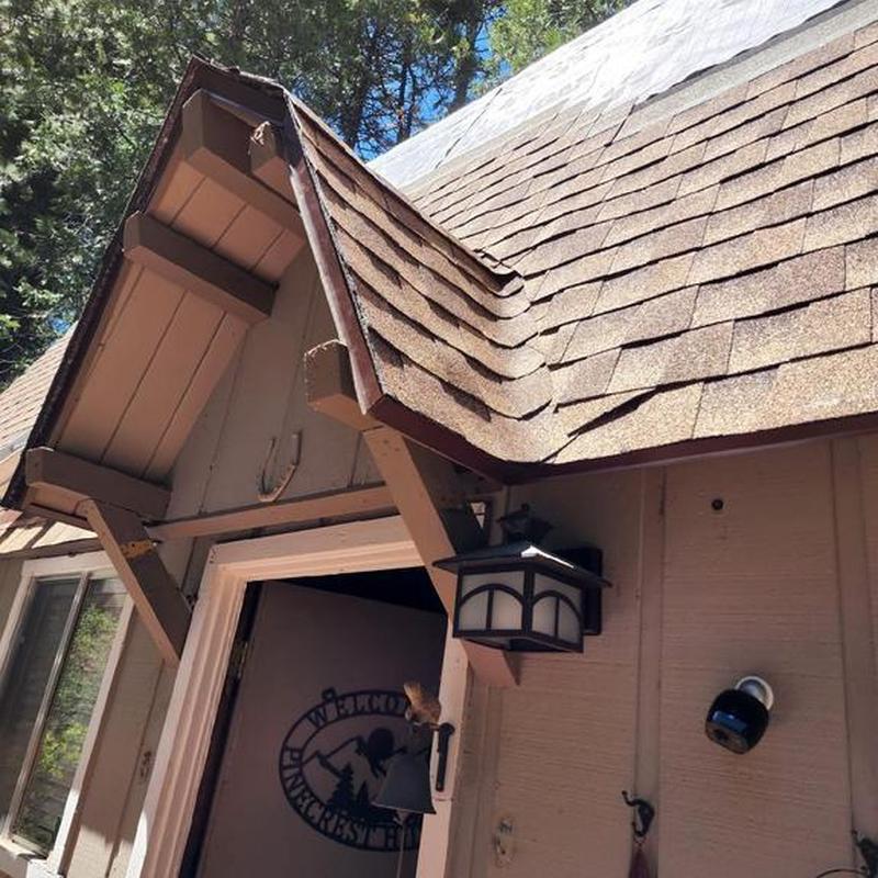 Asphalt shingle roof with visible damage on cabin
