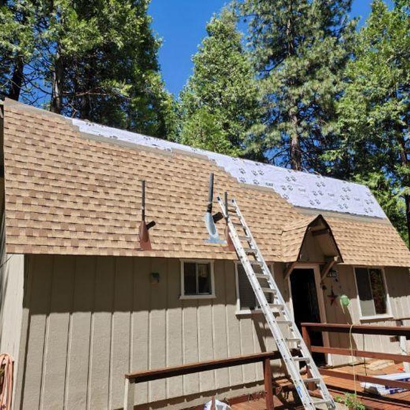 Asphalt shingle roof installation on cabin in forest