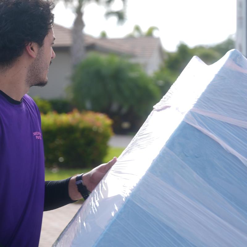 Wrapped mattress moving with red floor protection outdoors
