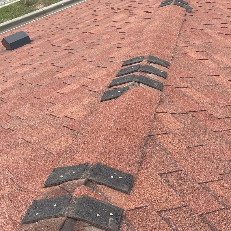 Asphalt shingle ridge with damaged caps on commercial roof