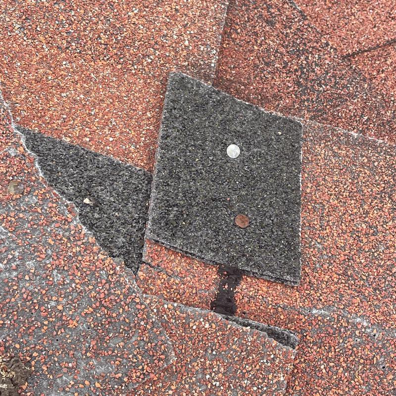 Asphalt shingle with nail and storm damage on roof