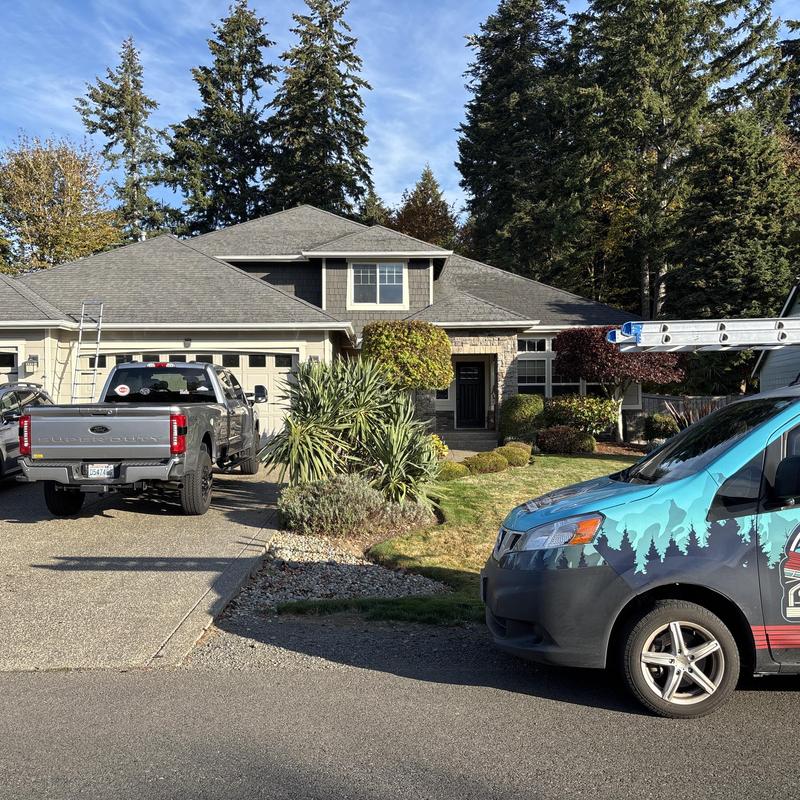 Asphalt shingle roof on suburban house with work vehicles