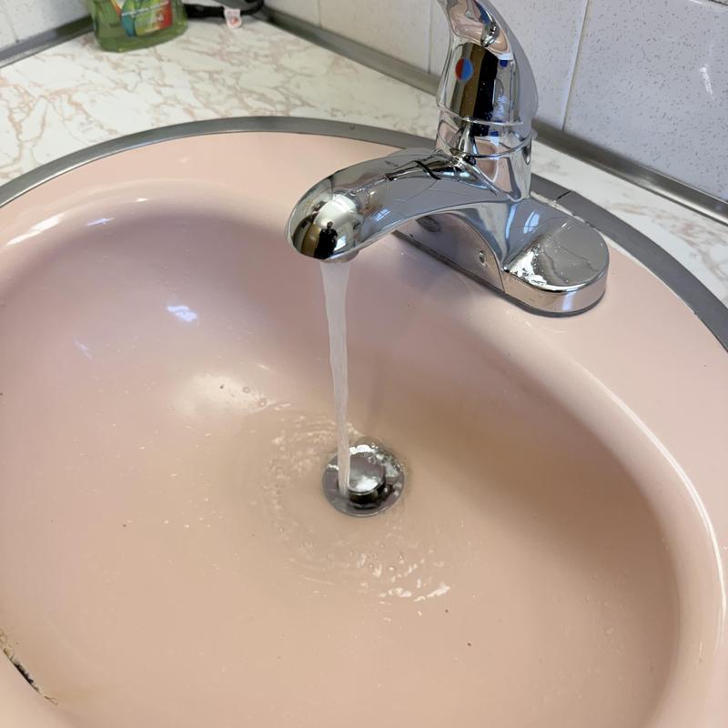 Lavatory drain with flowing water and chrome faucet