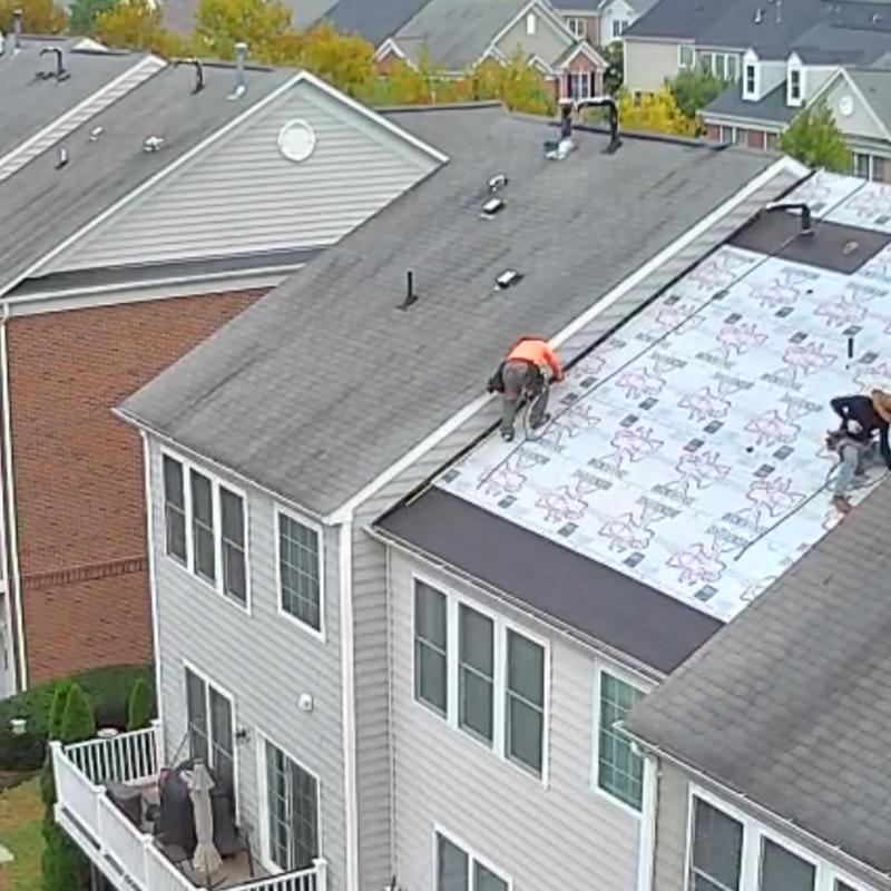 Roof underlayment installation with workers on slope Roof underlayment installation with workers on slope