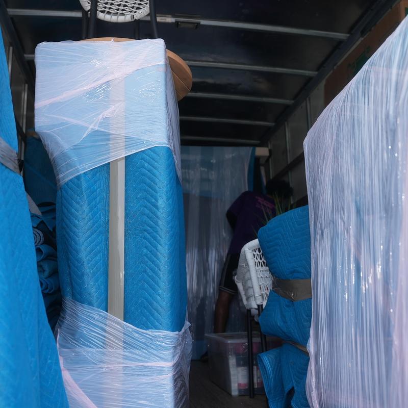 Furniture wrapped with blue moving blankets in truck