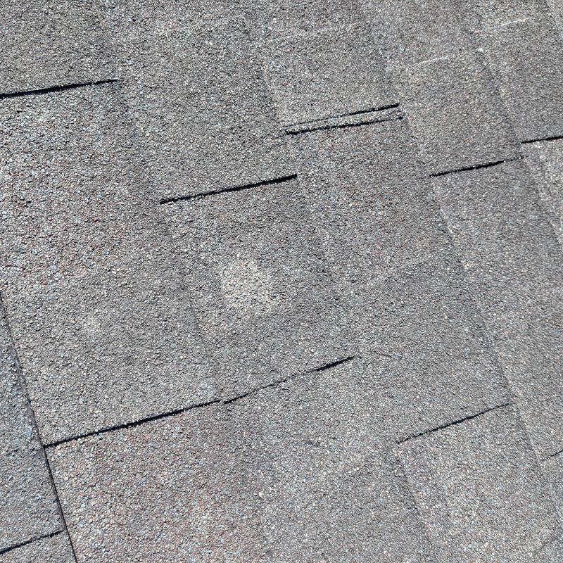 Asphalt roof shingles with visible hail damage spots