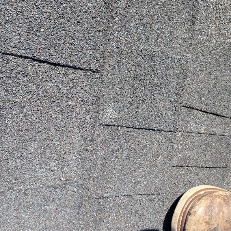 Asphalt roof shingles with hail damage and boot visible