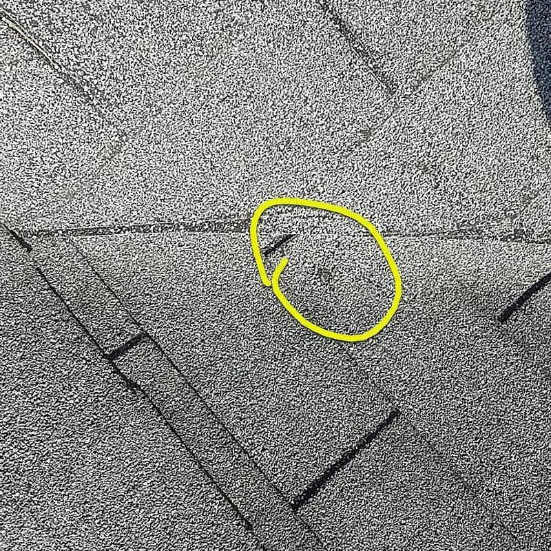 Shingle roof hail damage spot marked in yellow circle