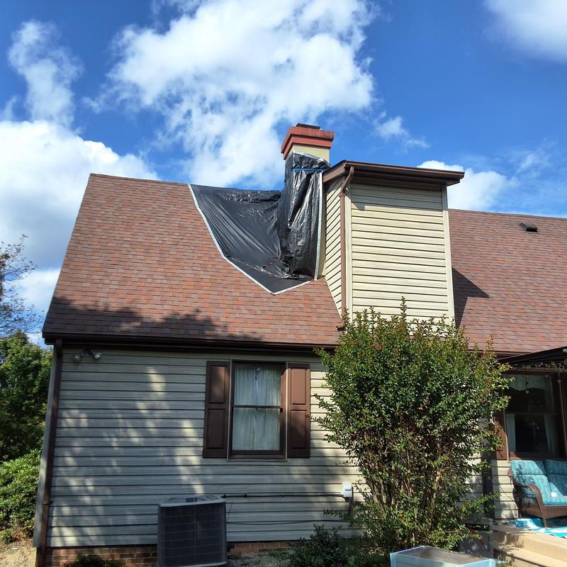Roof with tarp over leak near chimney on home exterior