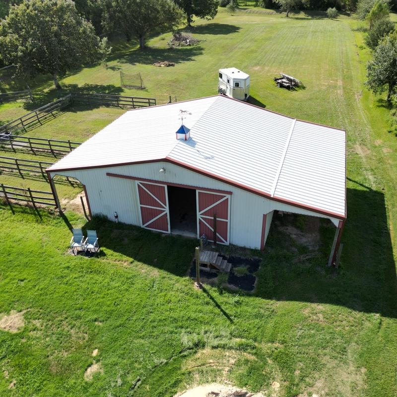 Metal barn roof with red trim in green yard
