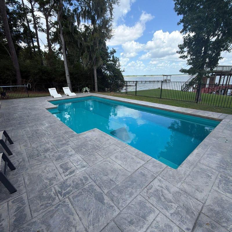 Fiberglass pool with concrete deck and lake view