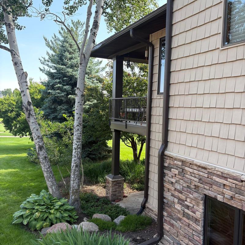 Gutter system with downspout on beige siding house Gutter system with downspout on beige siding house