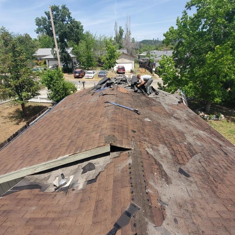 Asphalt shingle roof removal with roofer working