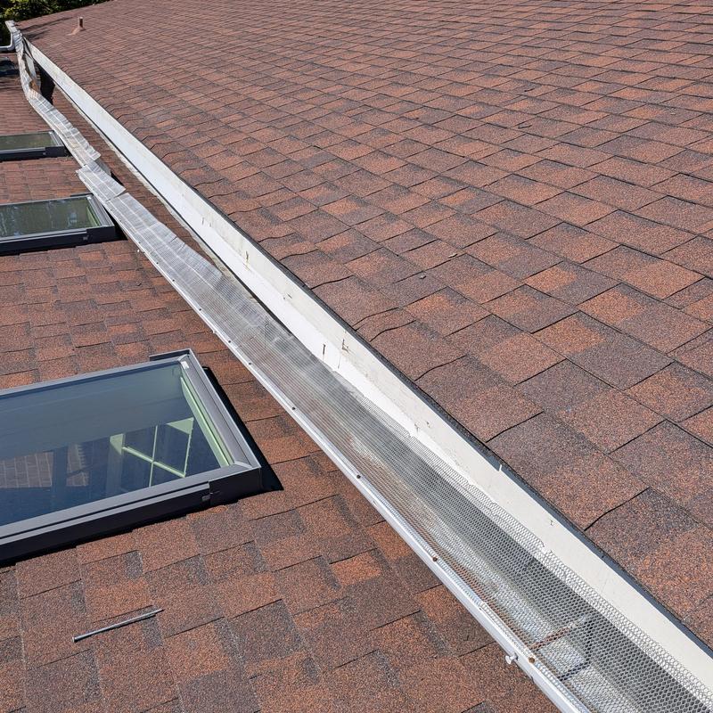 Gutter guard installation on shingle roof near skylights