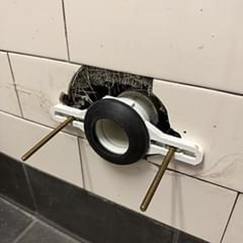 Urinal flange installed in tiled commercial restroom wall