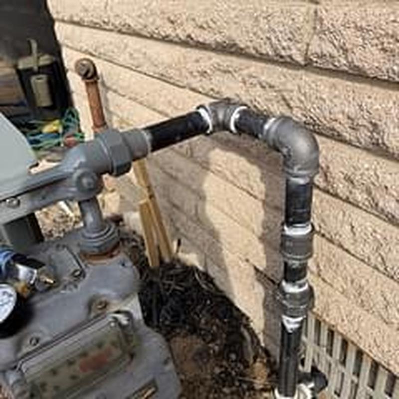 Gas meter piping into black 90 elbow by crawlspace wall
