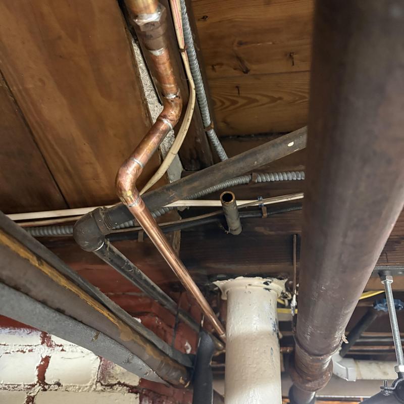 Copper water pipe rerouted around support beam in basement