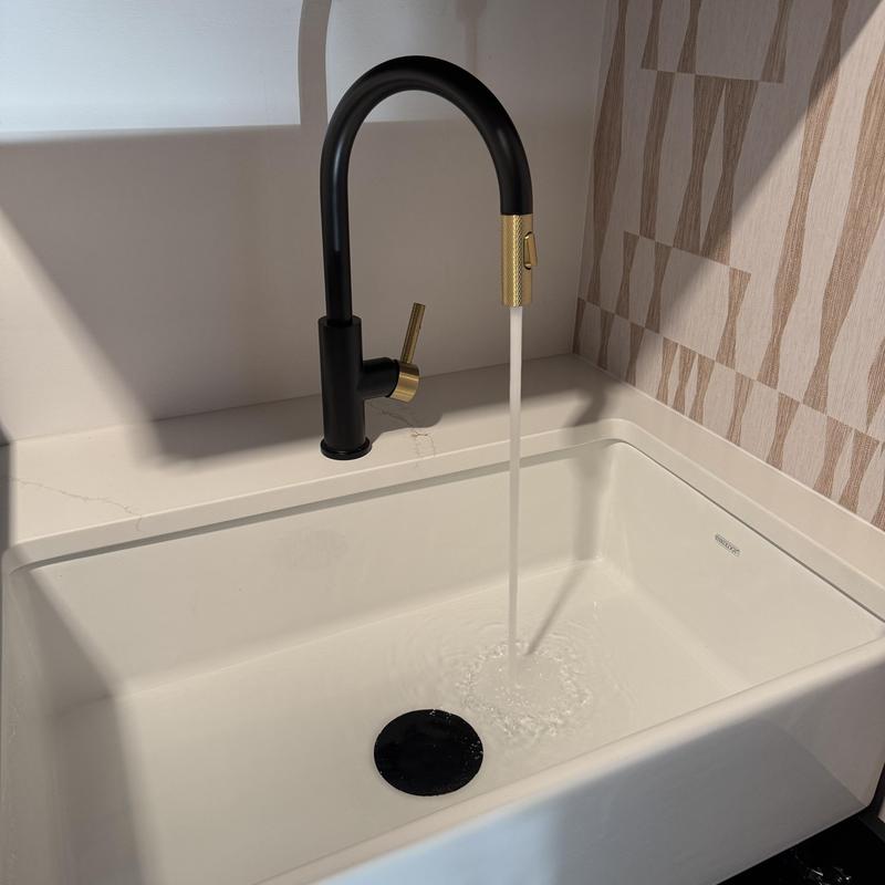 Undermount laundry sink with black and gold faucet flowing water Undermount laundry sink with black and gold faucet flowing water