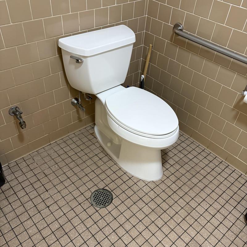 Toilet with replaced seal in tiled bathroom corner