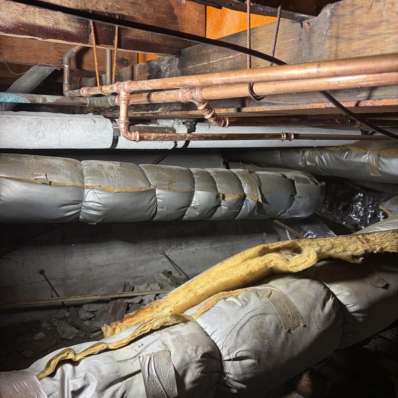 Copper water pipes with damaged insulation in crawl space