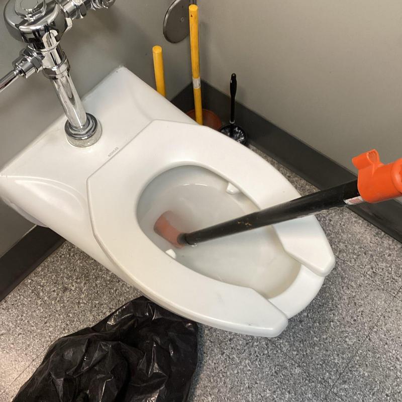 Toilet auger clearing blockage in commercial restroom
